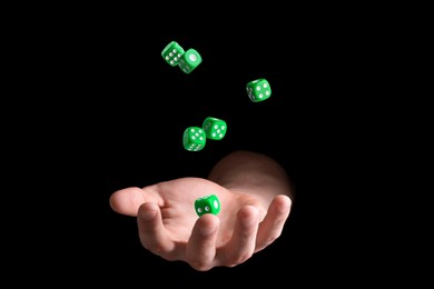 Image of Man throwing green dice on black background, closeup