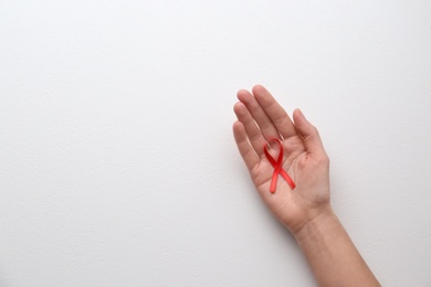 Photo of Woman holding red awareness ribbon on white background, top view with space for text. World AIDS disease day