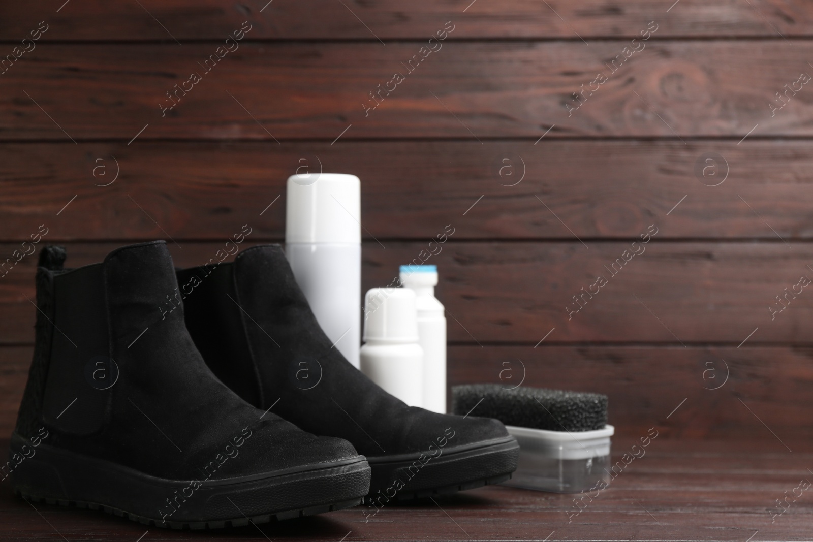 Photo of Stylish footwear with shoe care accessories on brown wooden table. Space for text
