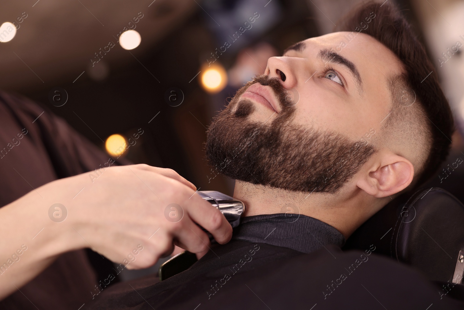 Photo of Professional hairdresser working with client in barbershop