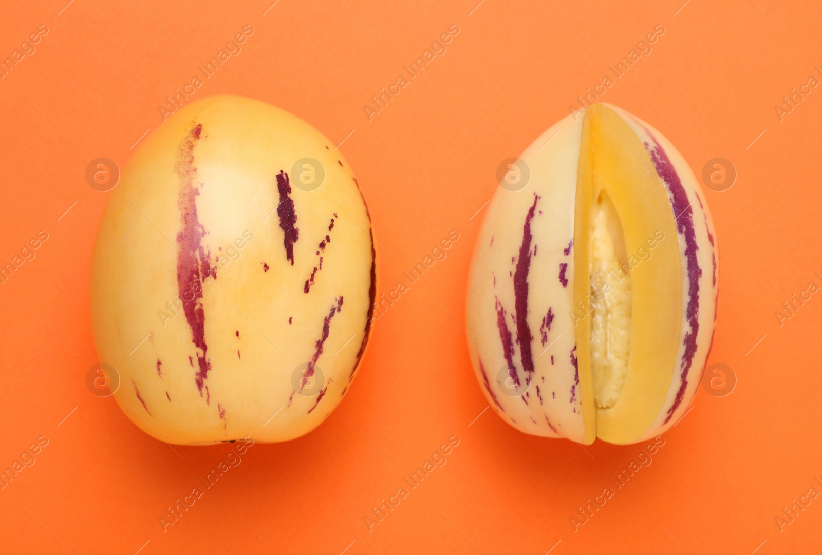 Photo of Whole and cut pepino melons on orange background, flat lay