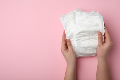 Photo of Woman with diapers on pink background, closeup. Space for text