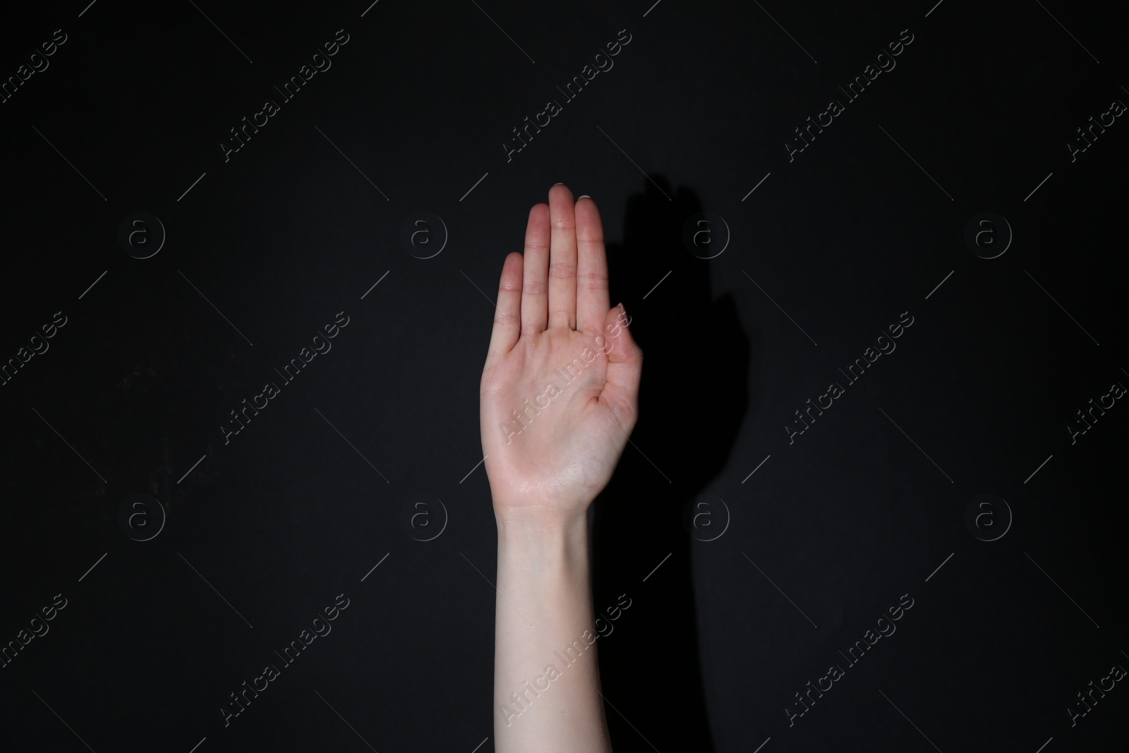 Photo of Woman showing open palm on black background, closeup