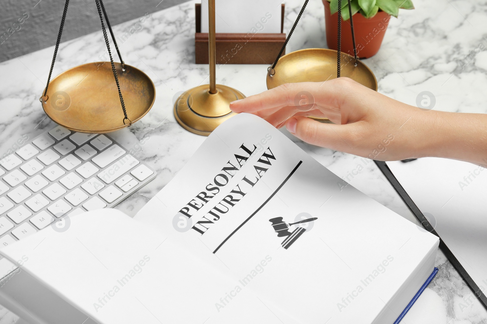 Photo of Woman turning page of book with words PERSONAL INJURY LAW at table, closeup