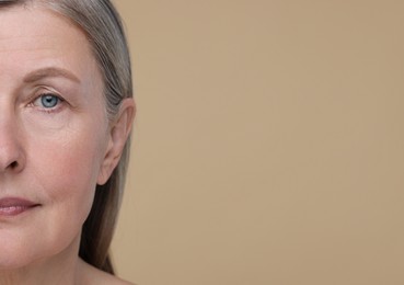 Photo of Senior woman with aging skin on beige background, closeup and space for text. Rejuvenation treatment