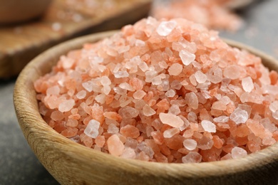 Photo of Pink himalayan salt in wooden bowl on table, closeup