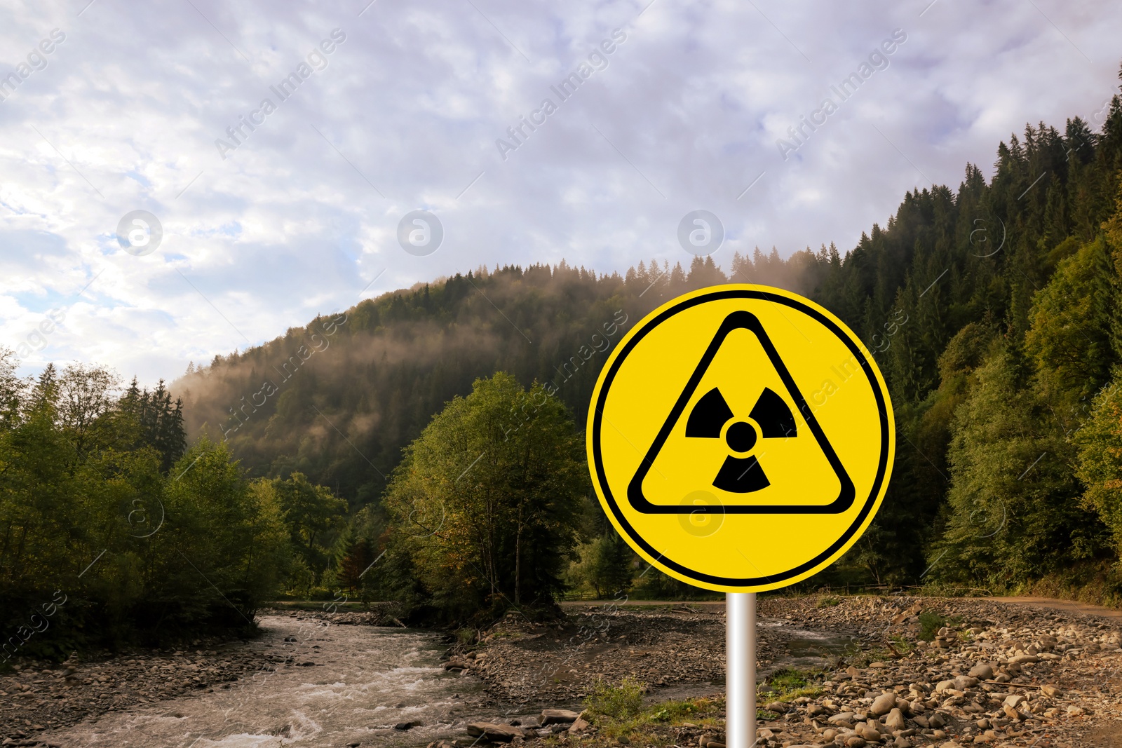 Image of Radioactive pollution. Yellow warning sign with hazard symbol in mountains