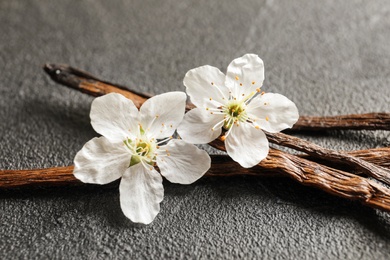 Photo of Vanilla sticks and flowers on grey background