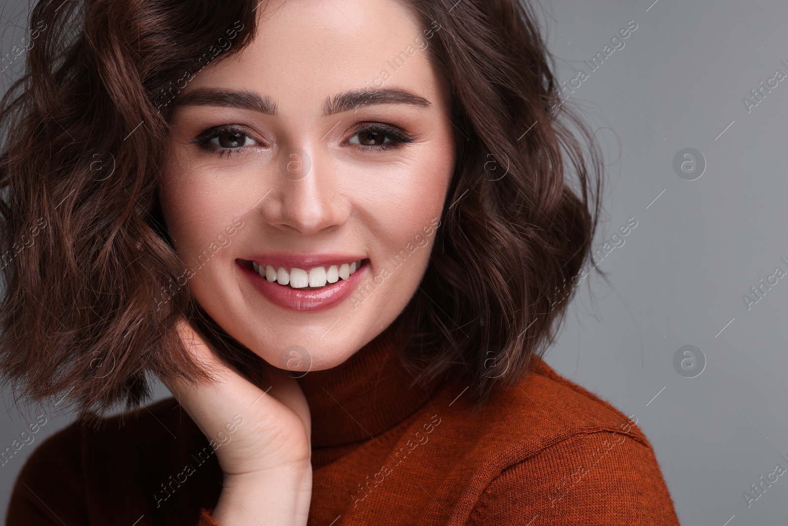 Photo of Beautiful young woman with wavy hairstyle on grey background