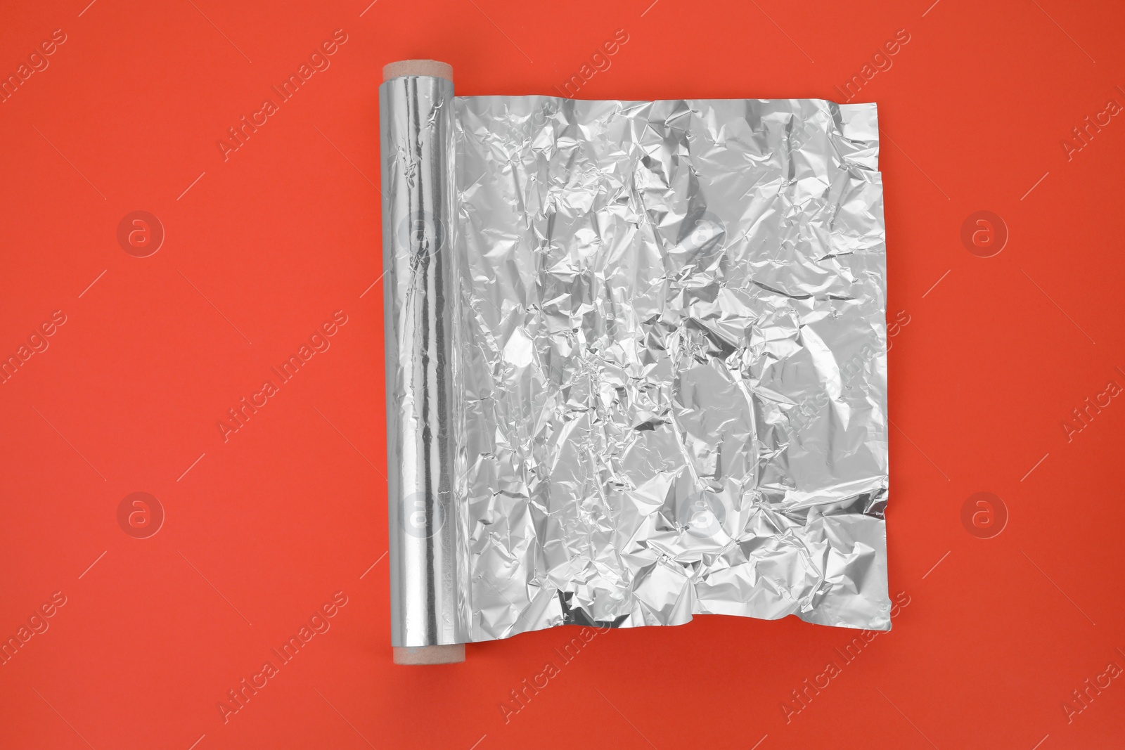 Photo of Roll of aluminum foil on orange background, top view