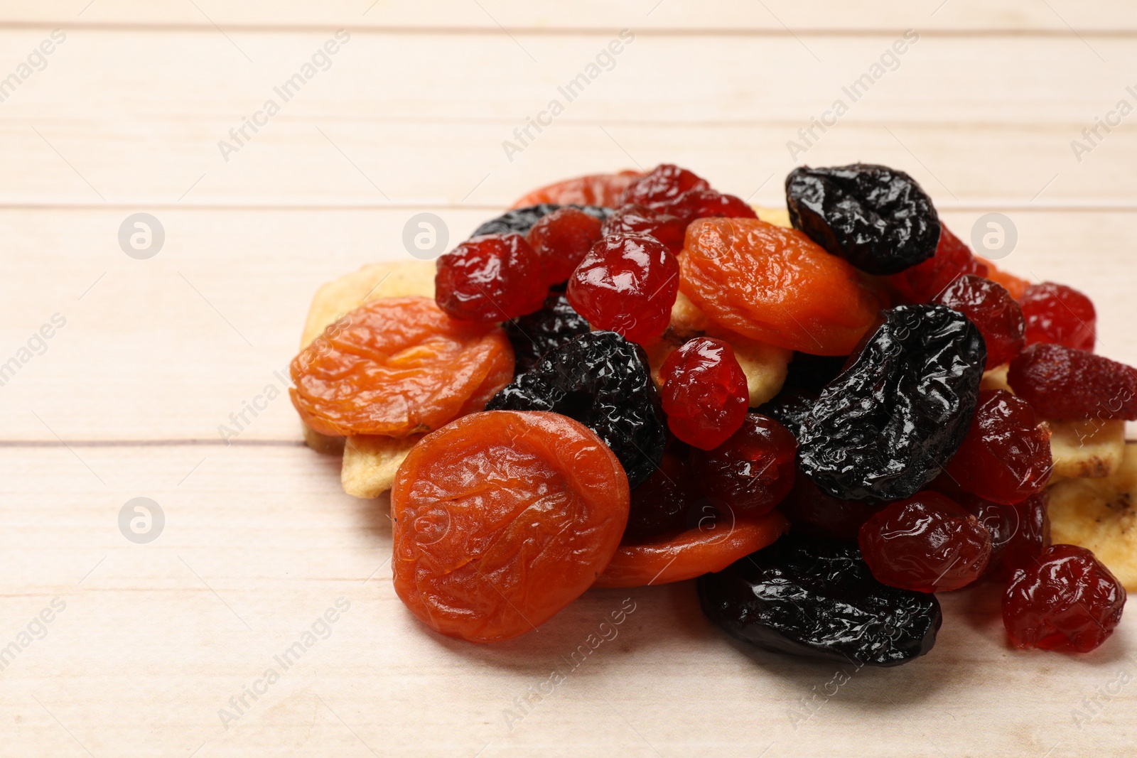 Photo of Mix of delicious dried fruits on white wooden table, closeup. Space for text