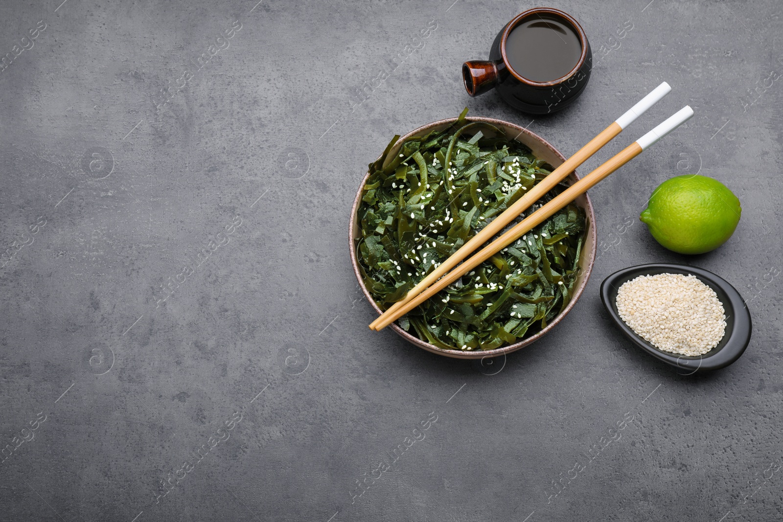 Photo of Fresh laminaria (kelp) seaweed served on gray table, flat lay. Space for text