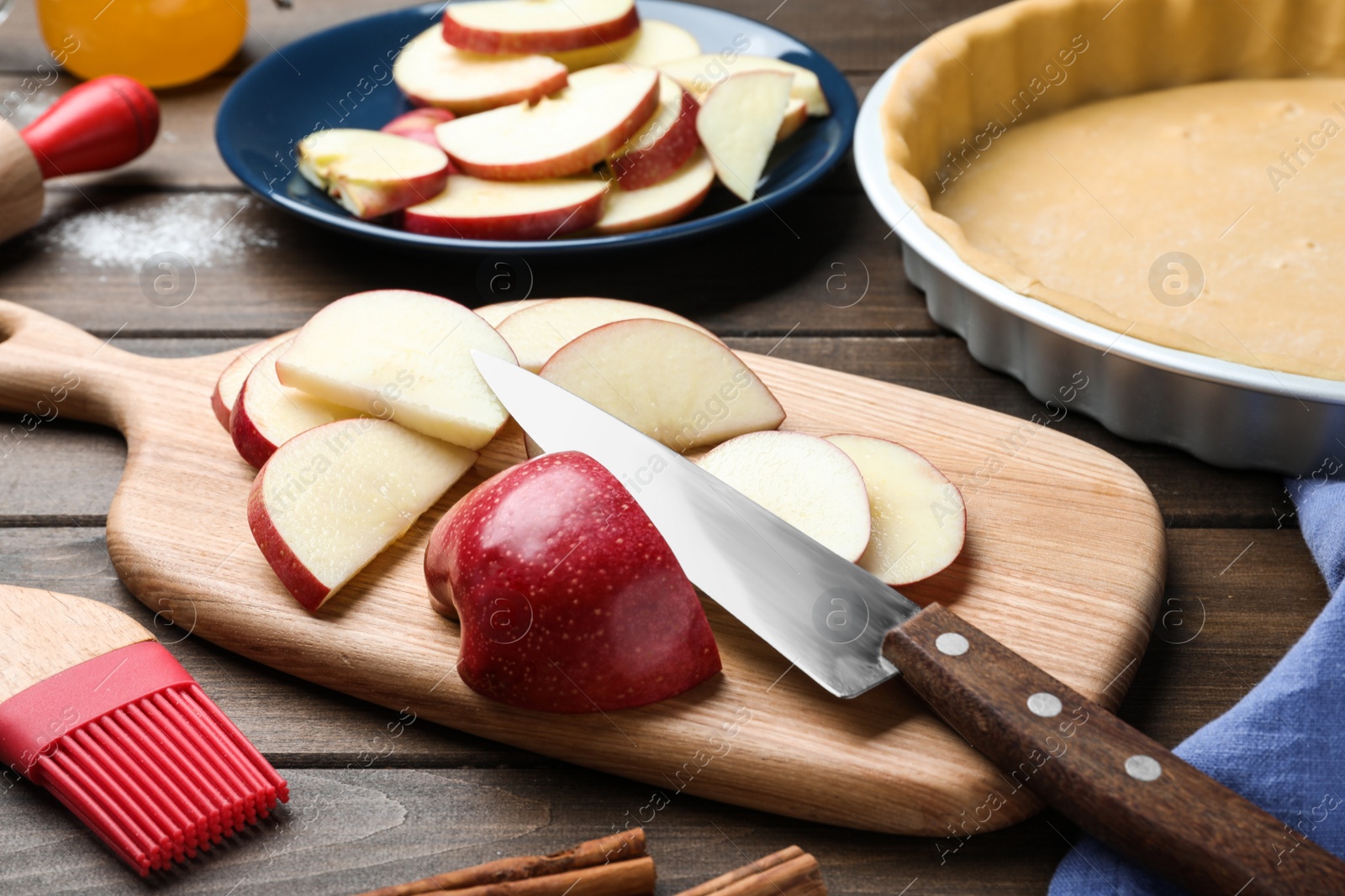 Photo of Cut fresh apple with knife and board on wooden table. Baking pie