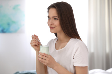 Young attractive woman with tasty yogurt at home