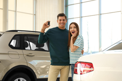 Photo of Happy couple with car key in modern auto dealership