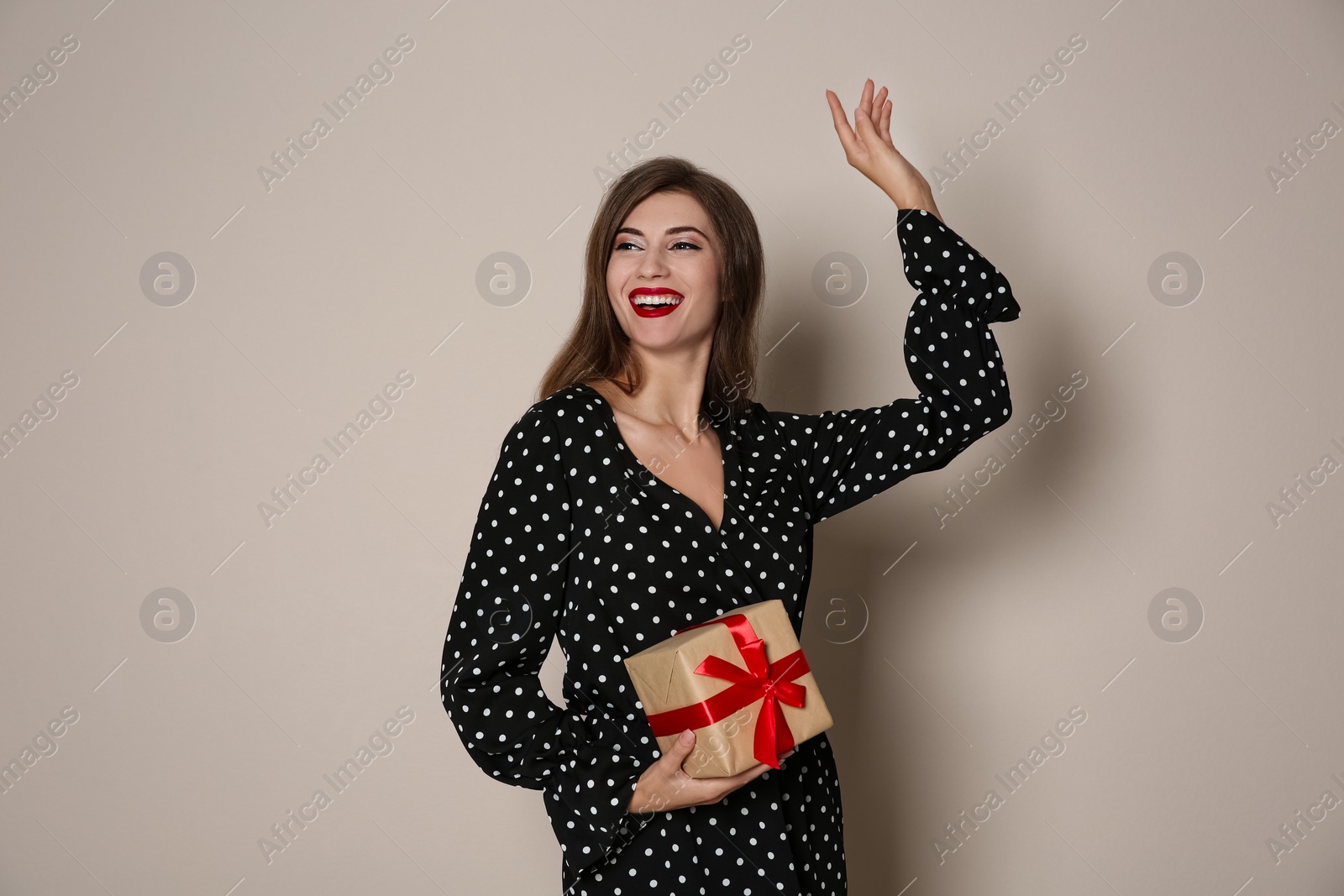 Photo of Happy woman with gift box on beige background. Christmas party