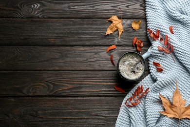 Flat lay composition with hot drink and warm plaid on black wooden table, space for text