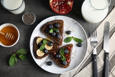 Different toasts with fruits, blueberries, honey and chia seeds served on table, top view