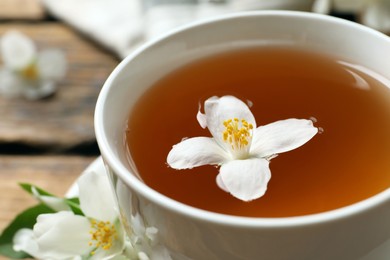 Cup of aromatic jasmine tea and fresh flowers, closeup