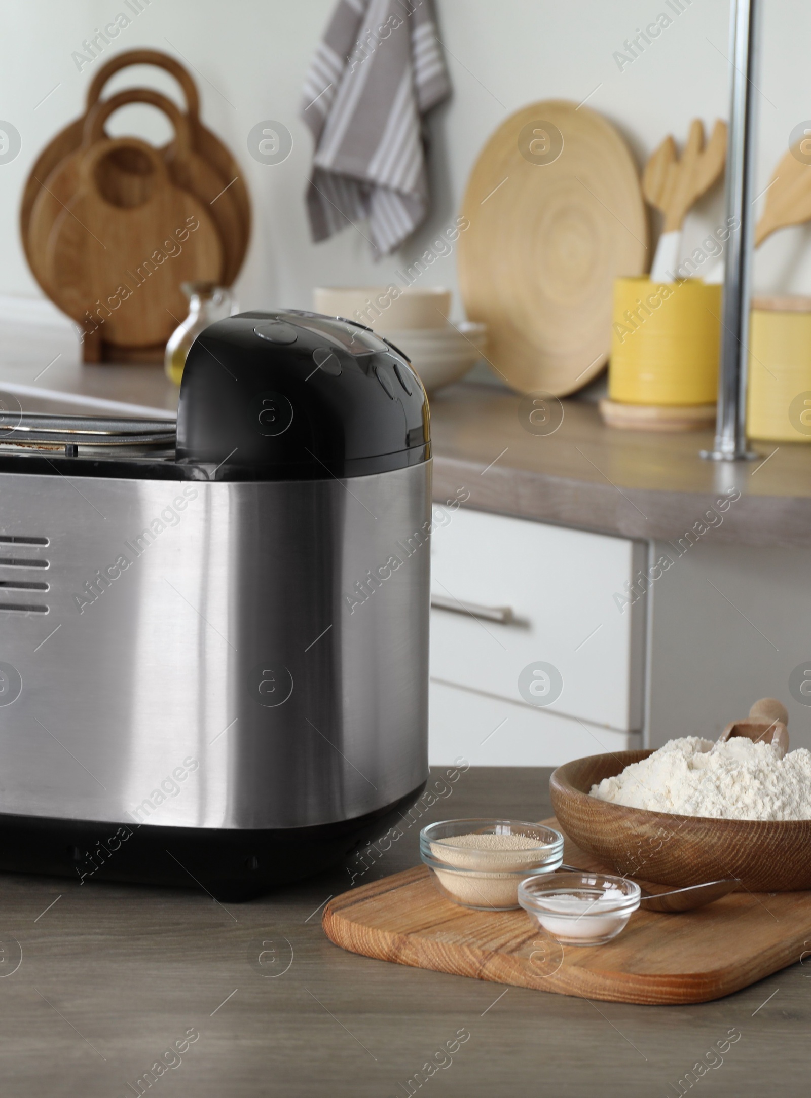 Photo of Breadmaker and products on wooden table in kitchen