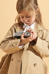 Fashion concept. Stylish girl with vintage camera on pale orange background