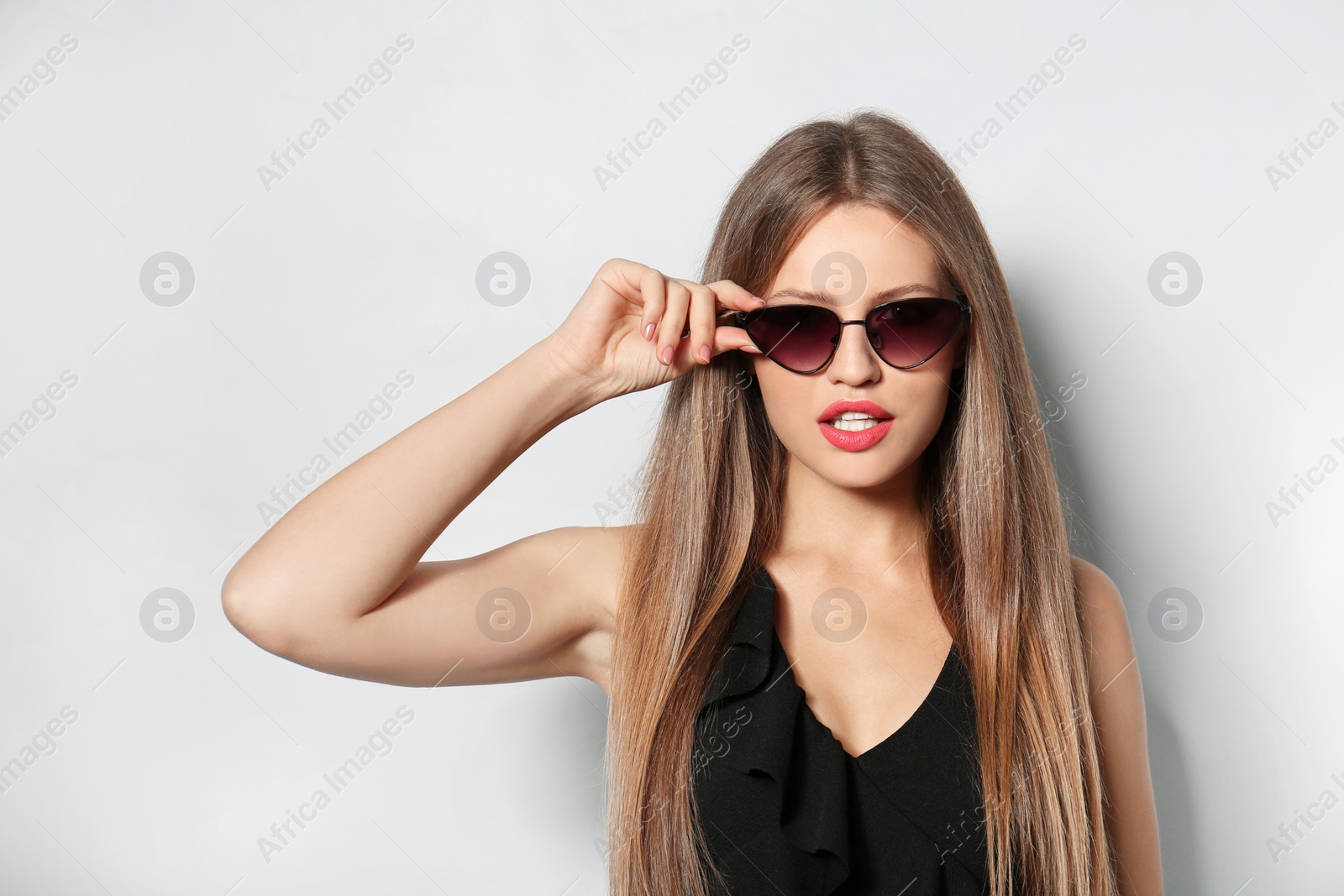 Photo of Young woman wearing stylish sunglasses on light background