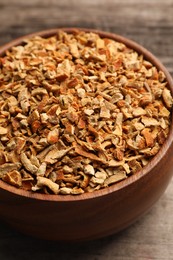 Photo of Bowl of dried orange zest seasoning on wooden table, closeup