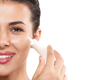 Photo of Woman applying cream under eyes on white background, closeup. Skin care