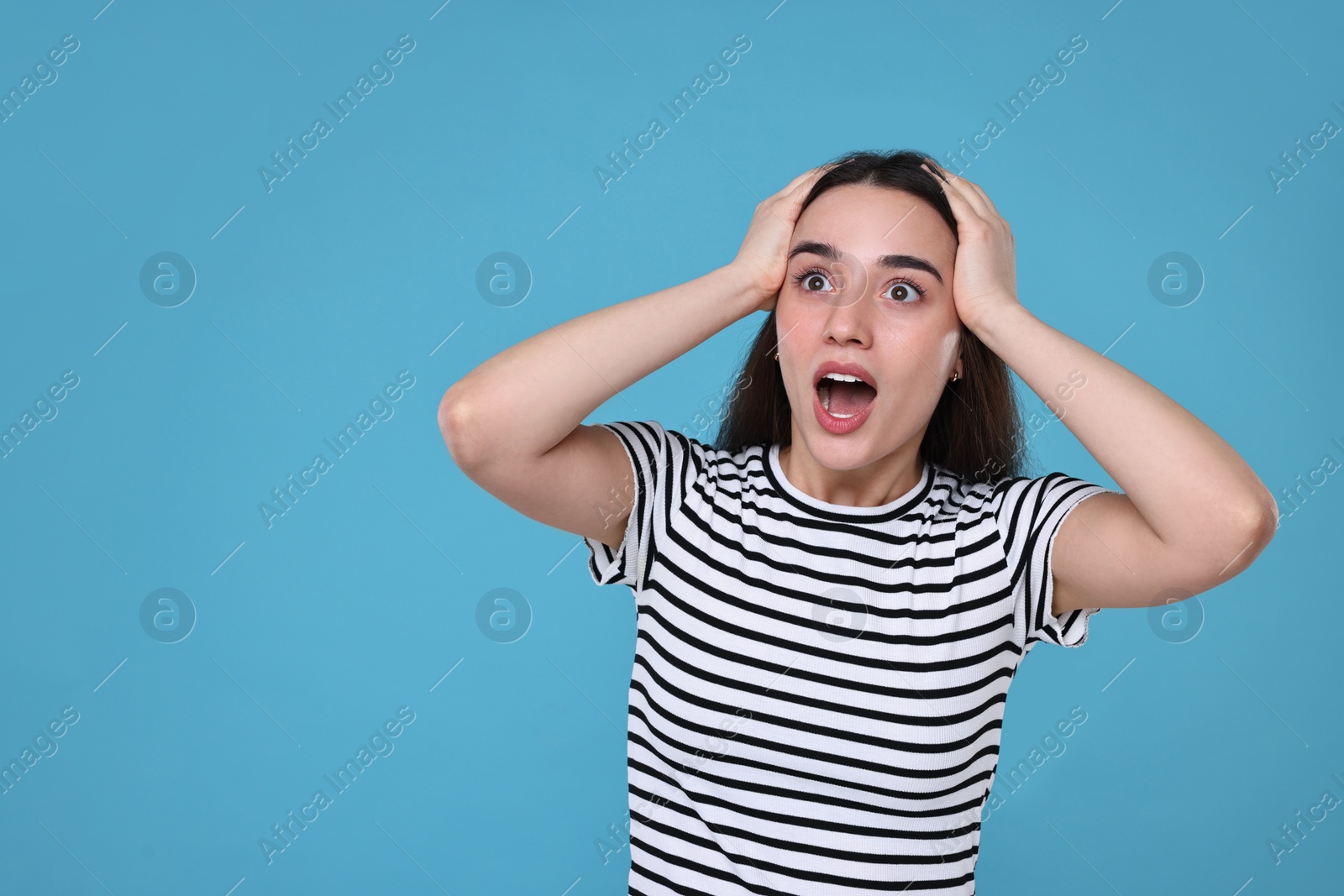 Photo of Portrait of surprised woman on light blue background. Space for text