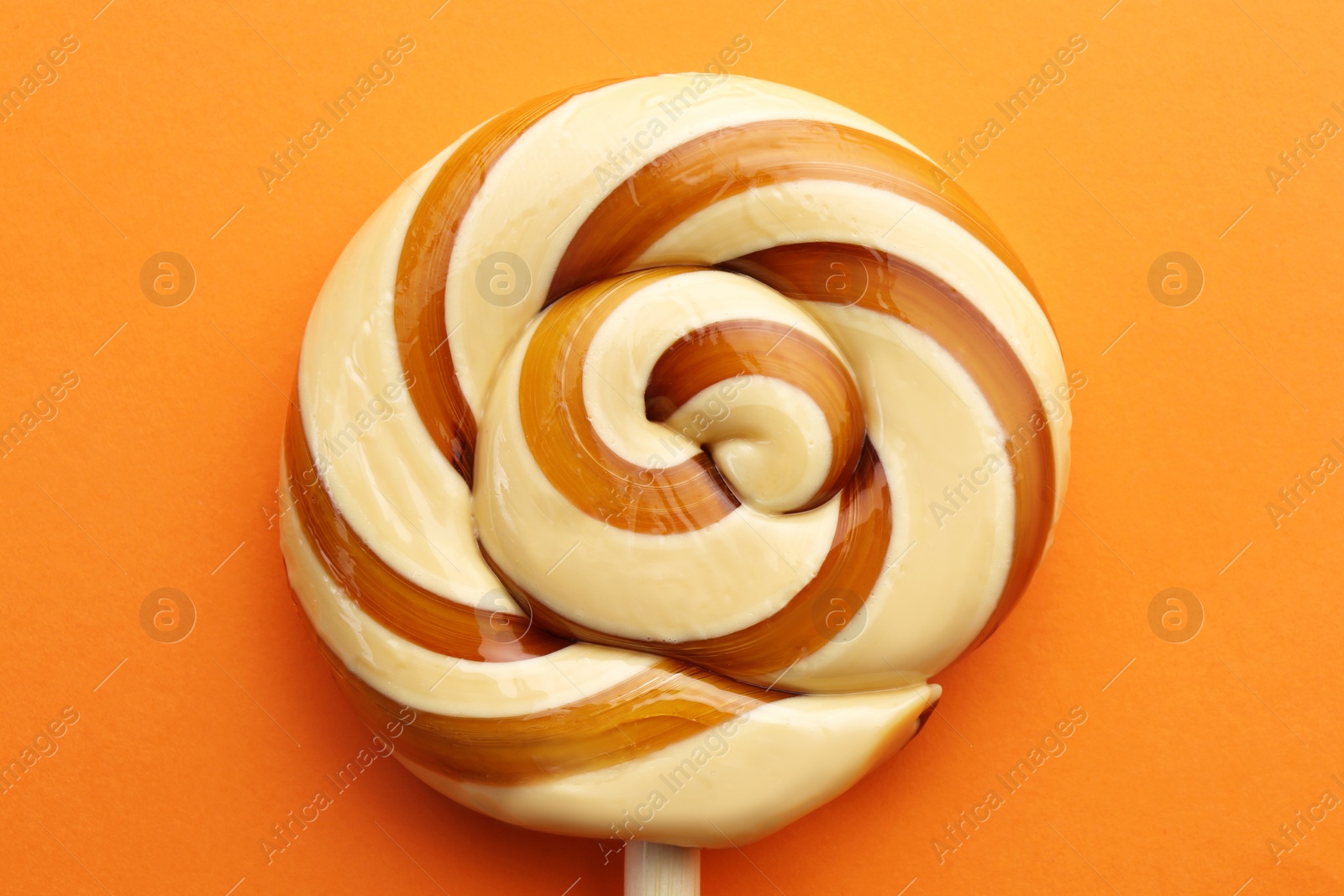 Photo of Sweet colorful lollipop on orange background, top view