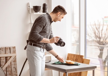 Young man with professional camera preparing food composition in photo studio