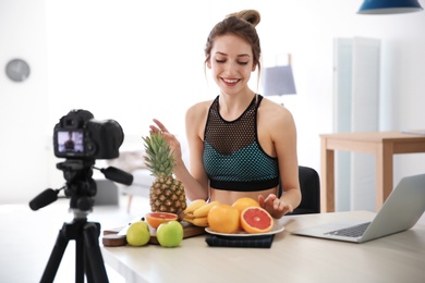 Young blogger with fruits recording video on kitchen