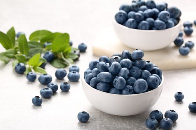 Tasty fresh blueberries on light grey table, closeup