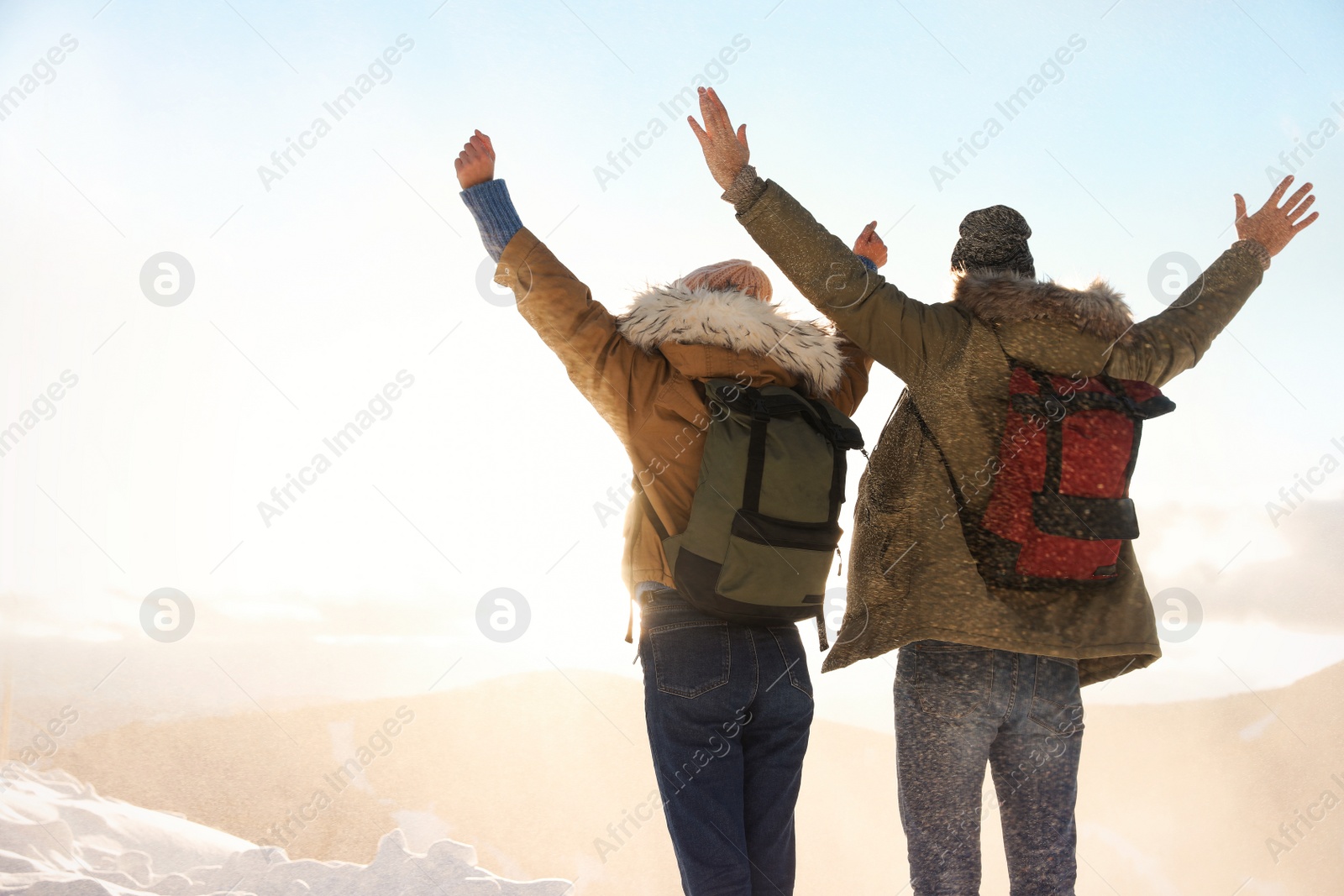 Photo of Excited couple with backpacks enjoying mountain view during winter vacation. Space for text