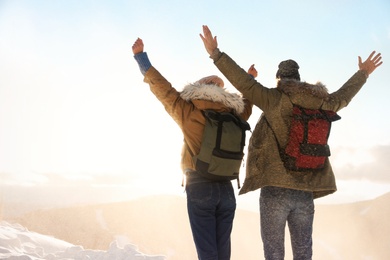 Excited couple with backpacks enjoying mountain view during winter vacation. Space for text