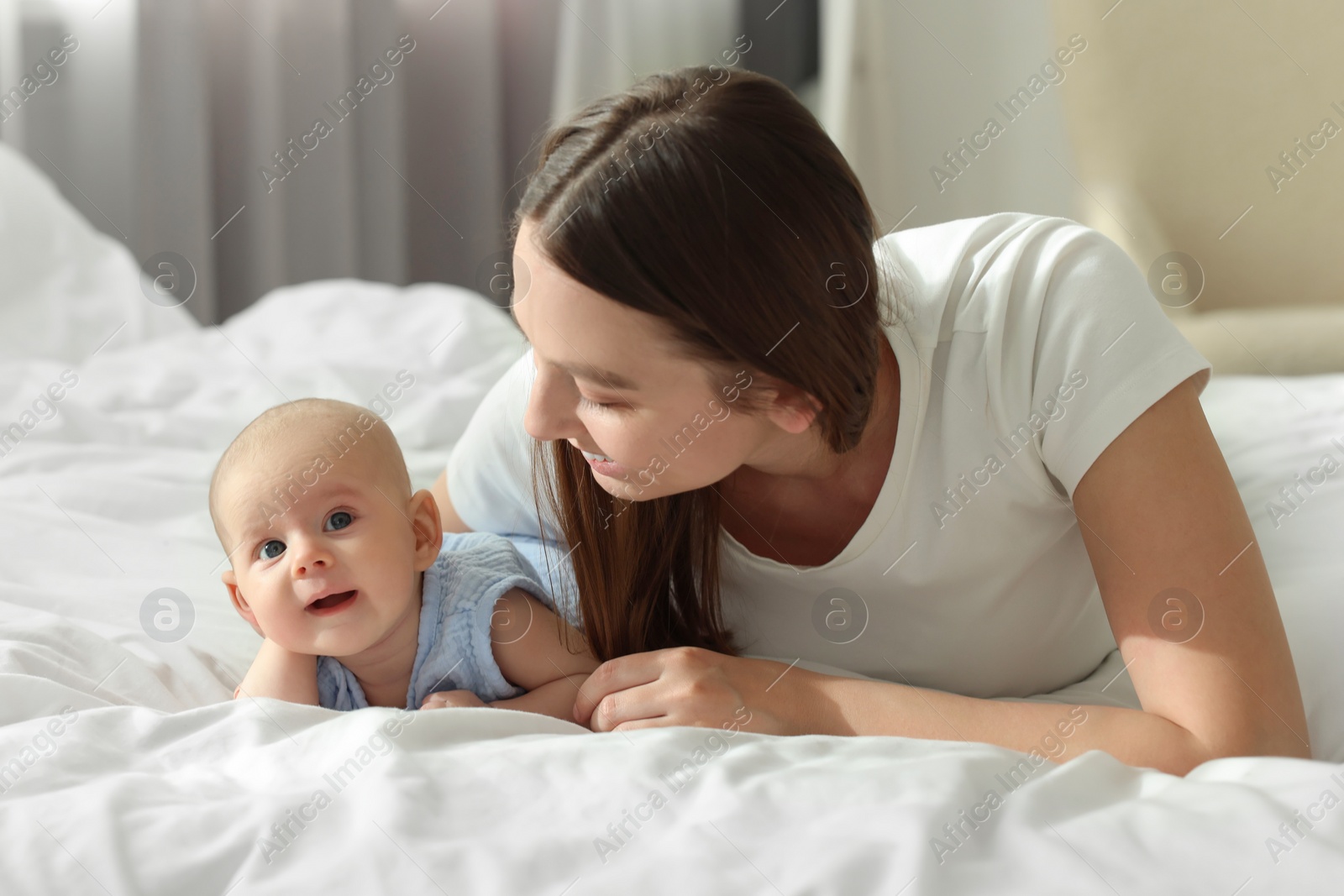 Photo of Mother with her cute baby on bed indoors