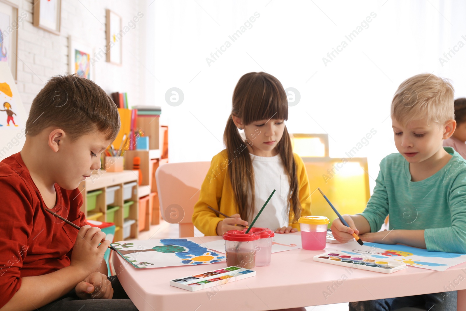 Photo of Cute little children painting at table in room