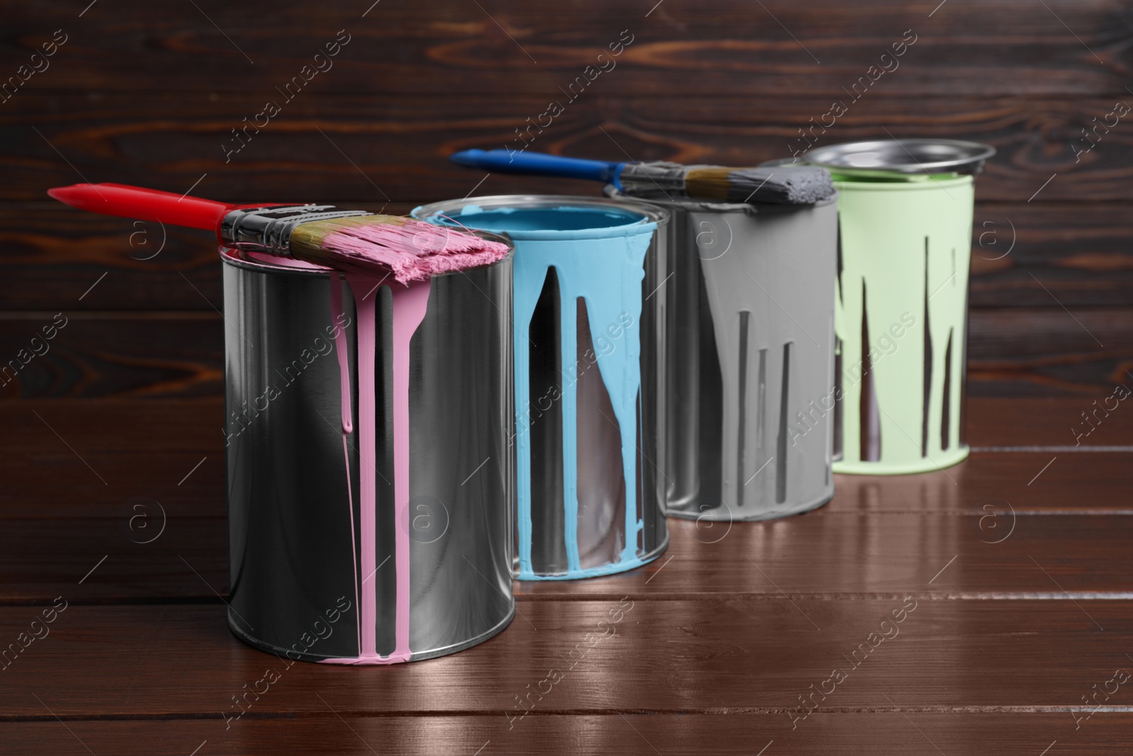 Photo of Cans of paints and brushes on wooden table