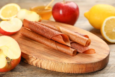 Photo of Delicious fruit leather rolls on wooden table, closeup