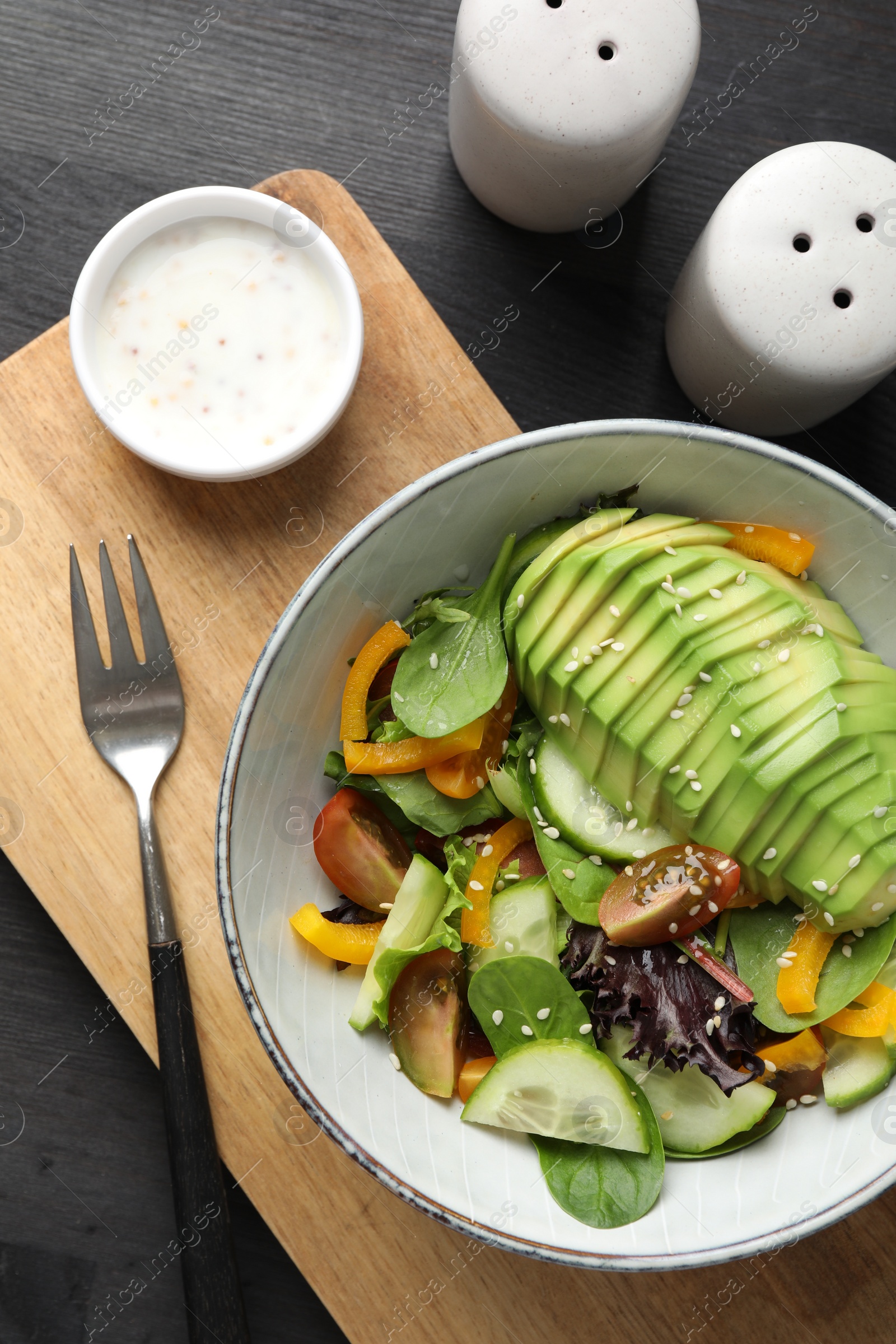 Photo of Healthy dish high in vegetable fats served on black wooden table, flat lay