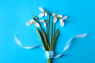 Photo of Beautiful snowdrops on light blue background, flat lay