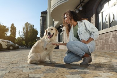 Photo of Young African-American woman and her Golden Retriever dog outdoors