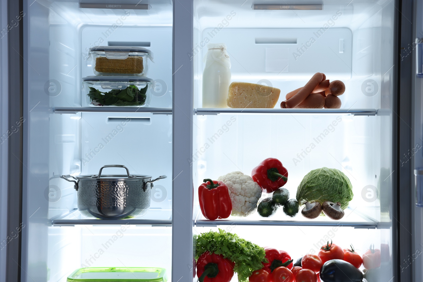 Photo of Open refrigerator full of different products indoors