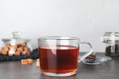 Photo of Cup of hot tea on table against blurred background