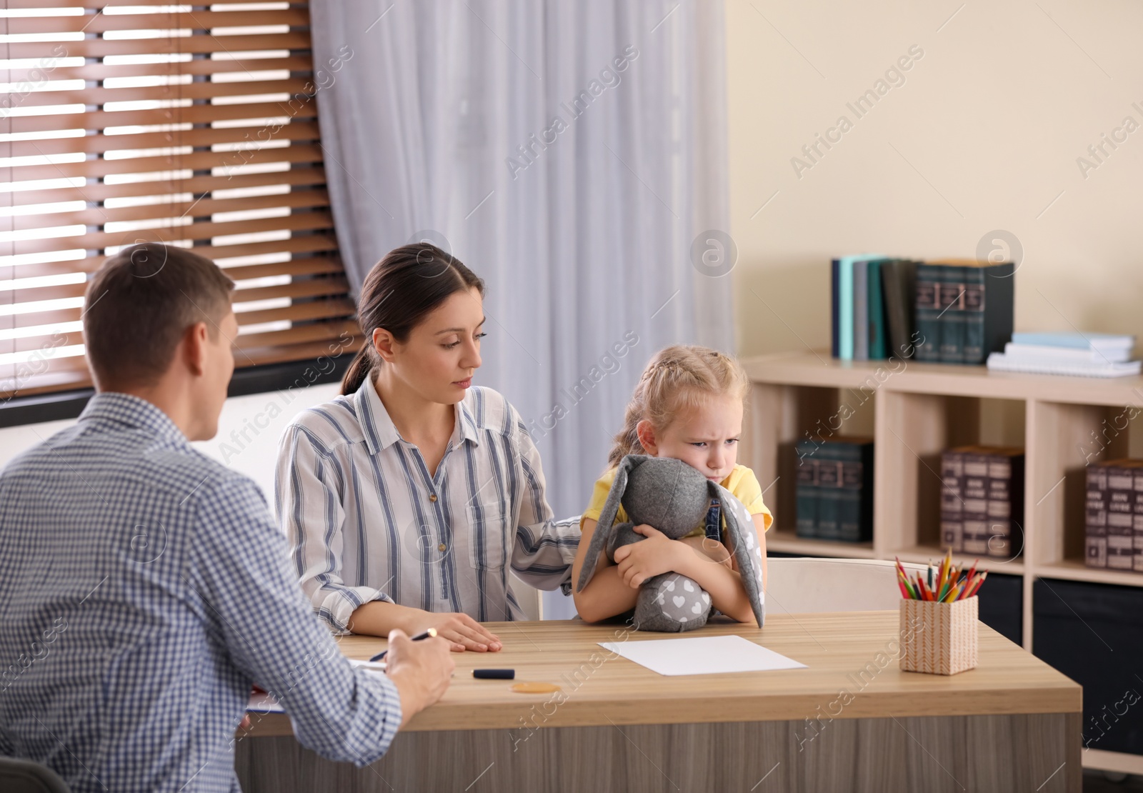 Photo of Child psychotherapist working with little girl and her mother in office