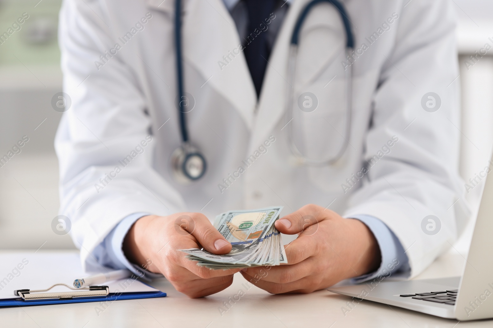 Photo of Doctor with bribe at desk in clinic, closeup. Corrupted medicine