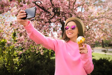 Happy woman taking selfie with ice cream in spring park