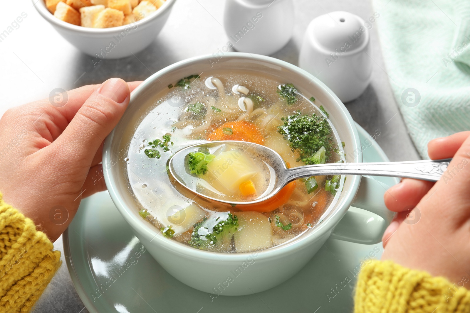 Photo of Woman eating fresh homemade vegetable soup at table, closeup