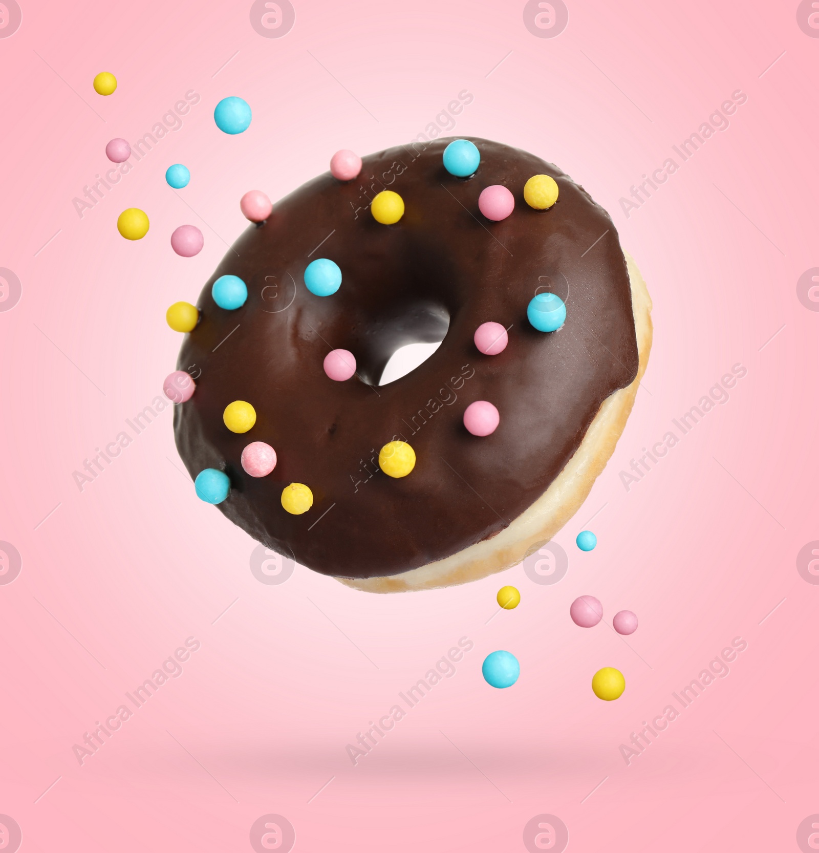 Image of Delicious sweet donut falling on pink background