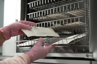 Photo of Professional manicurist putting tools into disinfection cabinet, closeup